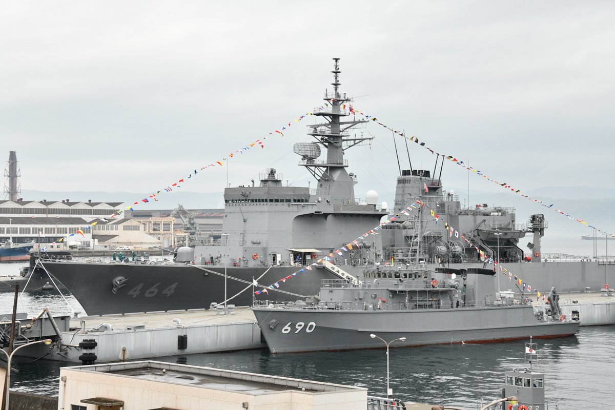 two gray ships with strings of flags at dock
