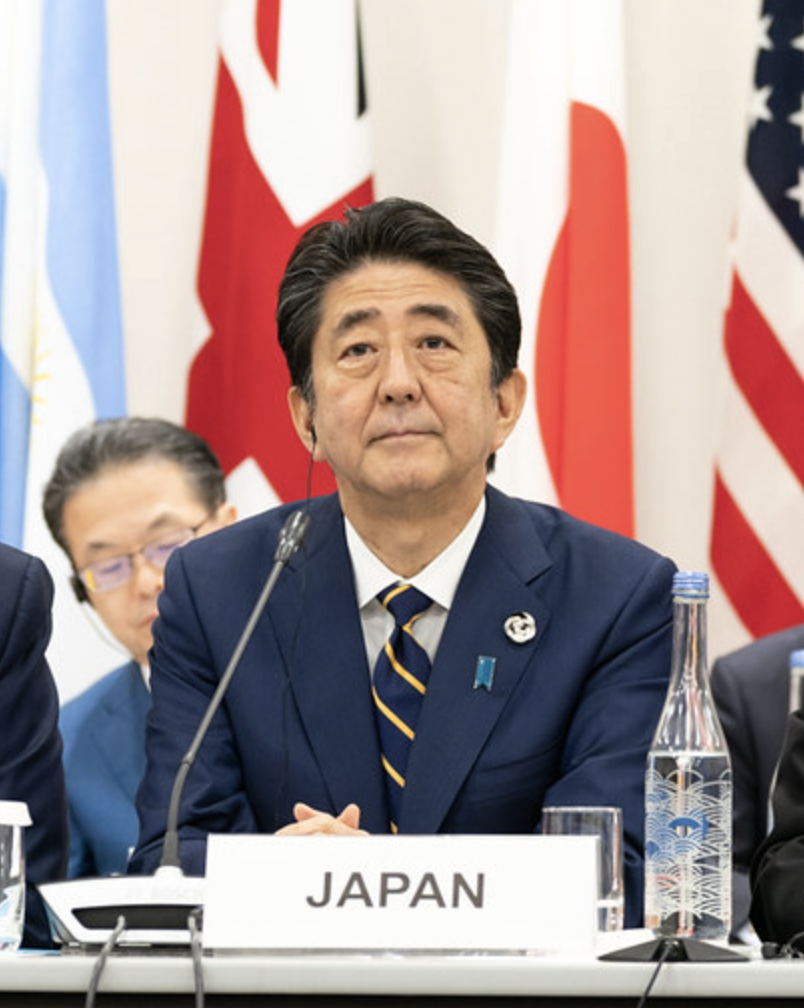 Japanese leader with JAPAN sign in table before him